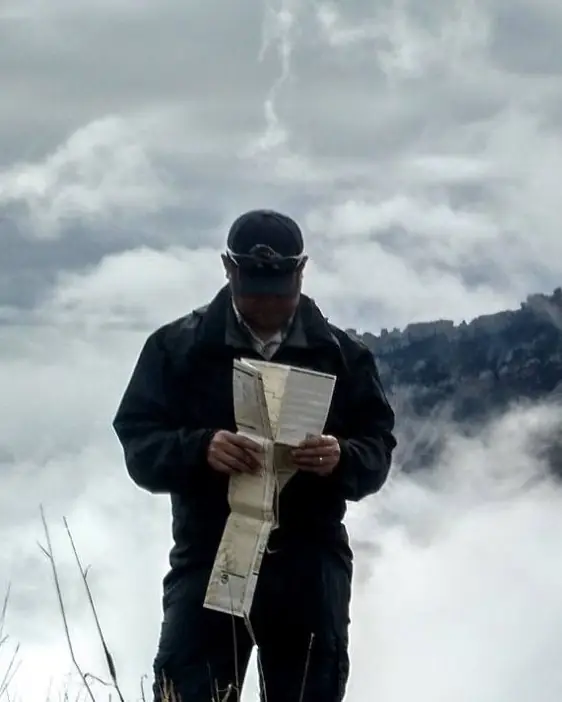 John Casiano reading a paper well log on a ridge above the clouds.